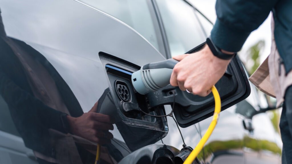 Hombre con enchufe de carga en auto electrico. Tipos de combustibles